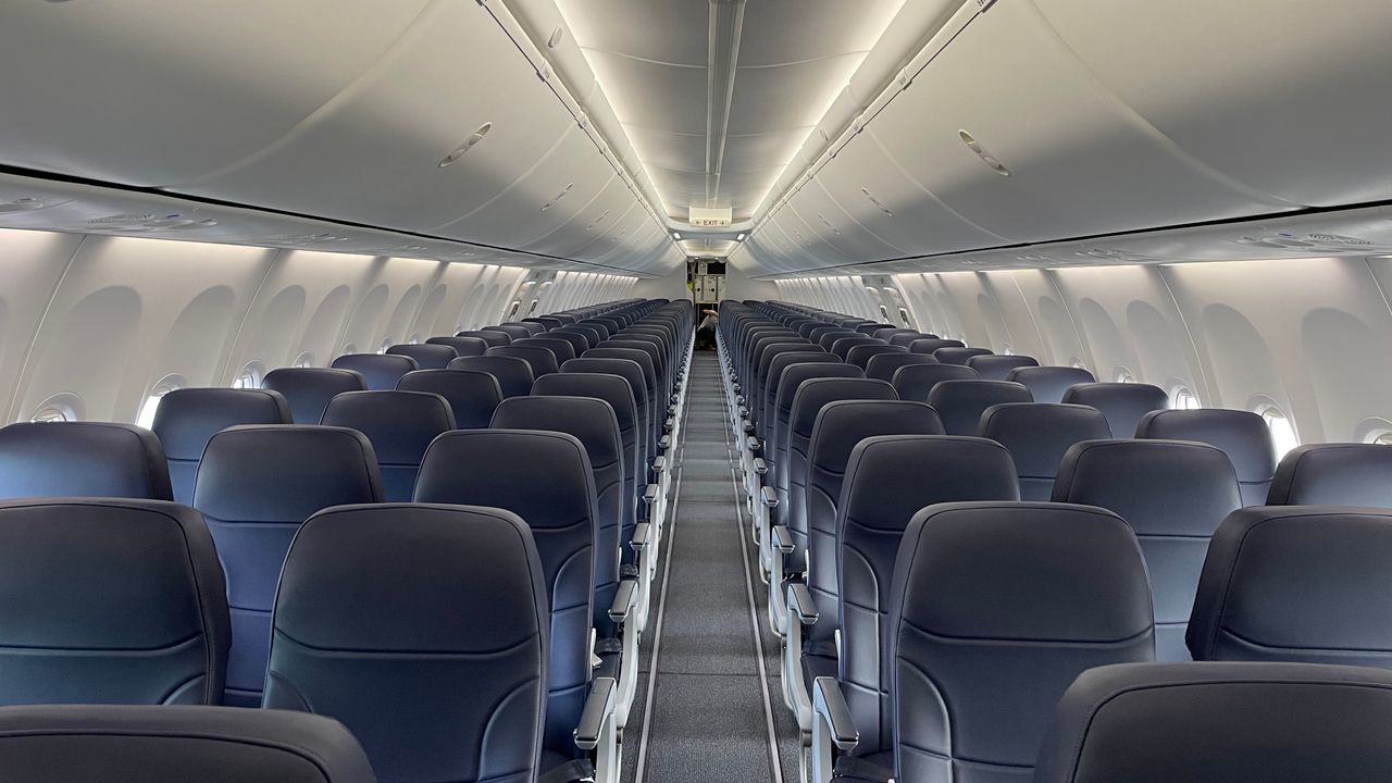 An aircraft cabin with rows of seats and overhead bins along both sides